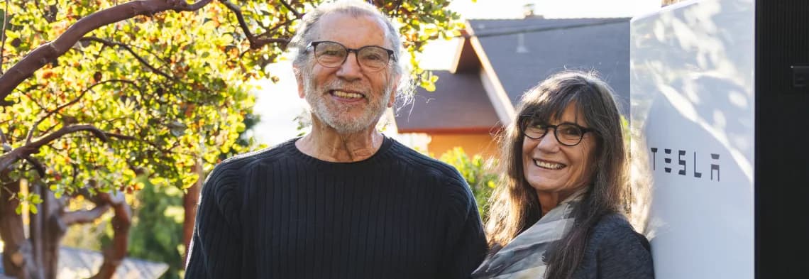 Two homeowners standing next to their SGIP-funded home battery